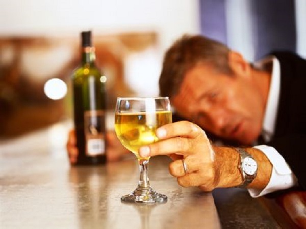 a young man sitting at the bar counter and checking the clarity of wine through a wine glass